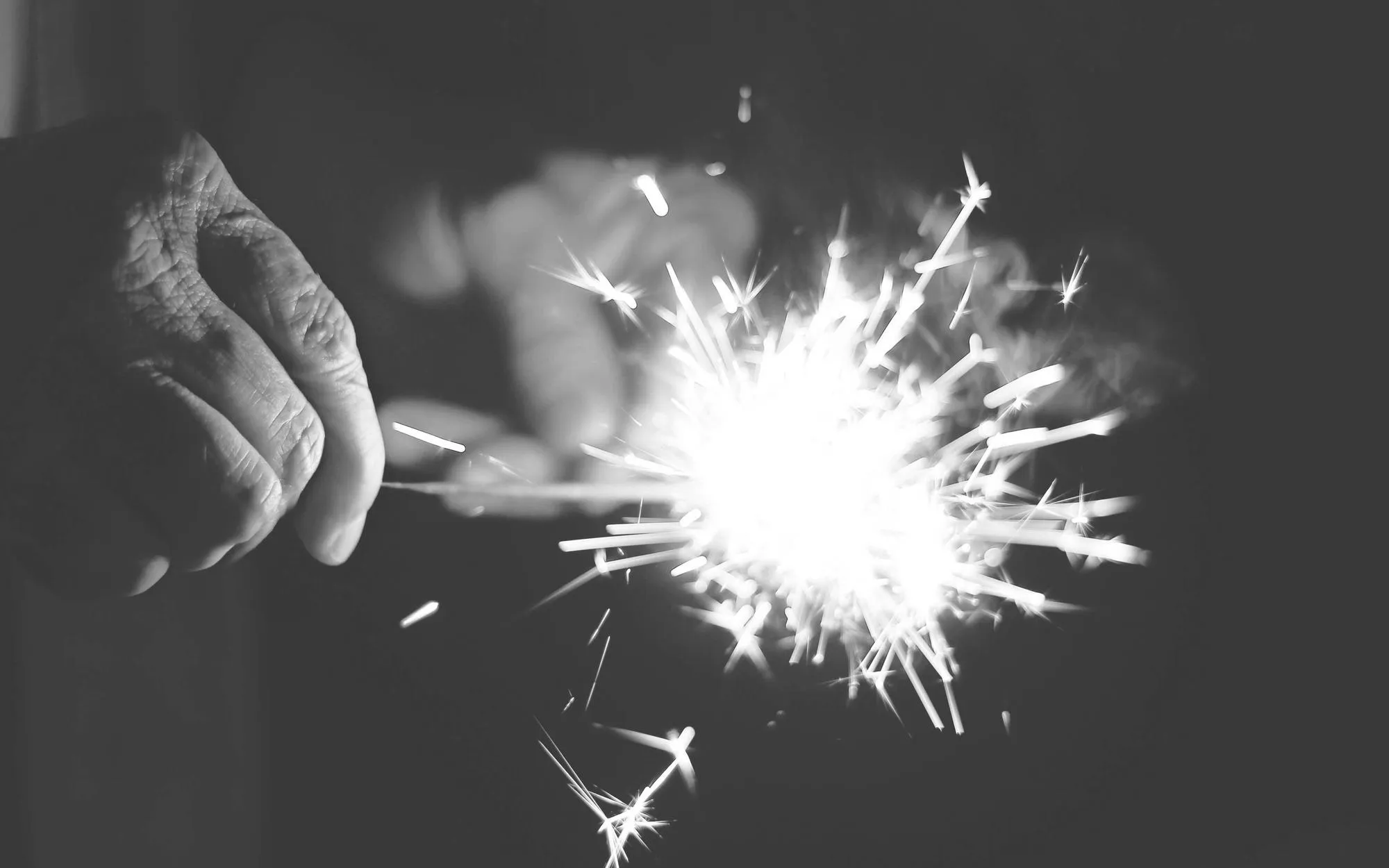 A sparkler throwing bright sparks in the dark, black and white