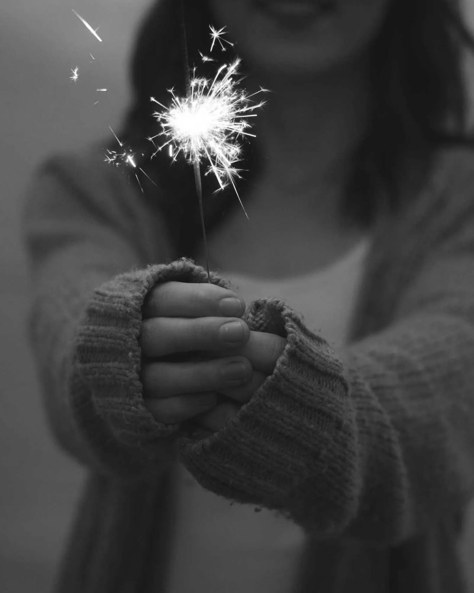 Hands holding a lit sparkler, black and white